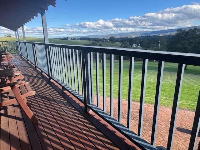 Covered timber verandah with painted balustrade overlooking an open lawn