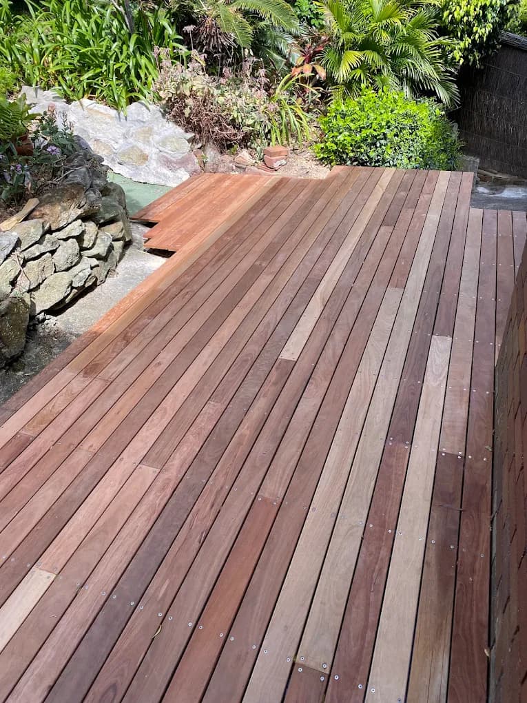 Timber deck meeting a stone retaining wall and established garden planting