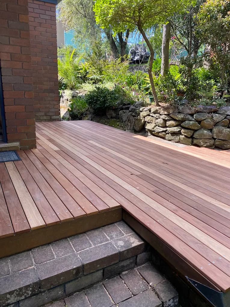 Timber decking beside a brick house, wrapping around existing paved steps