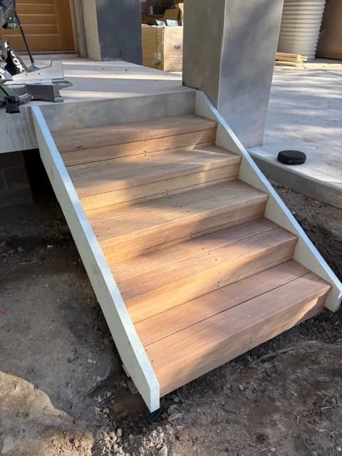 Timber entrance stairs with closed risers and pale painted stringers during construction