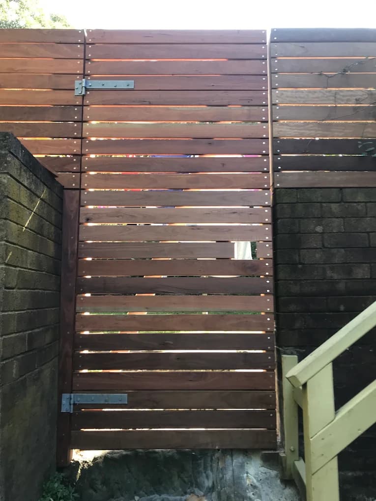 Horizontal timber slat gate and fence between masonry walls
